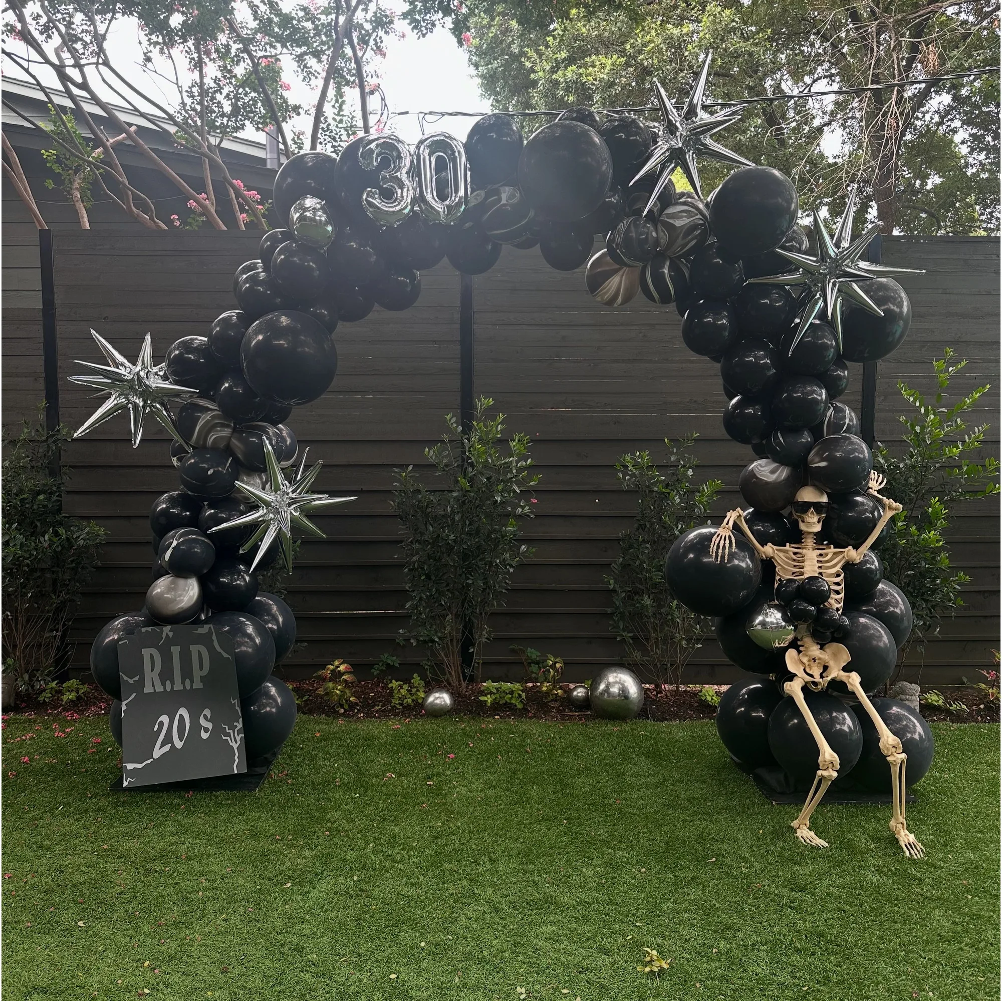 Black and silver thirtieth birthday balloon arch with skeleton decor