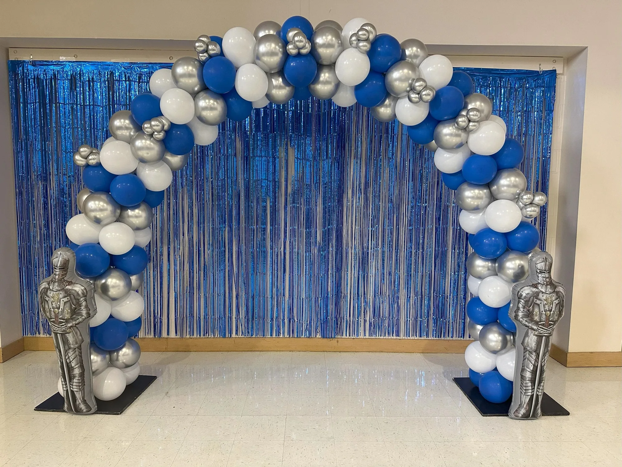 Blue, silver, and white balloon arch with knight figures