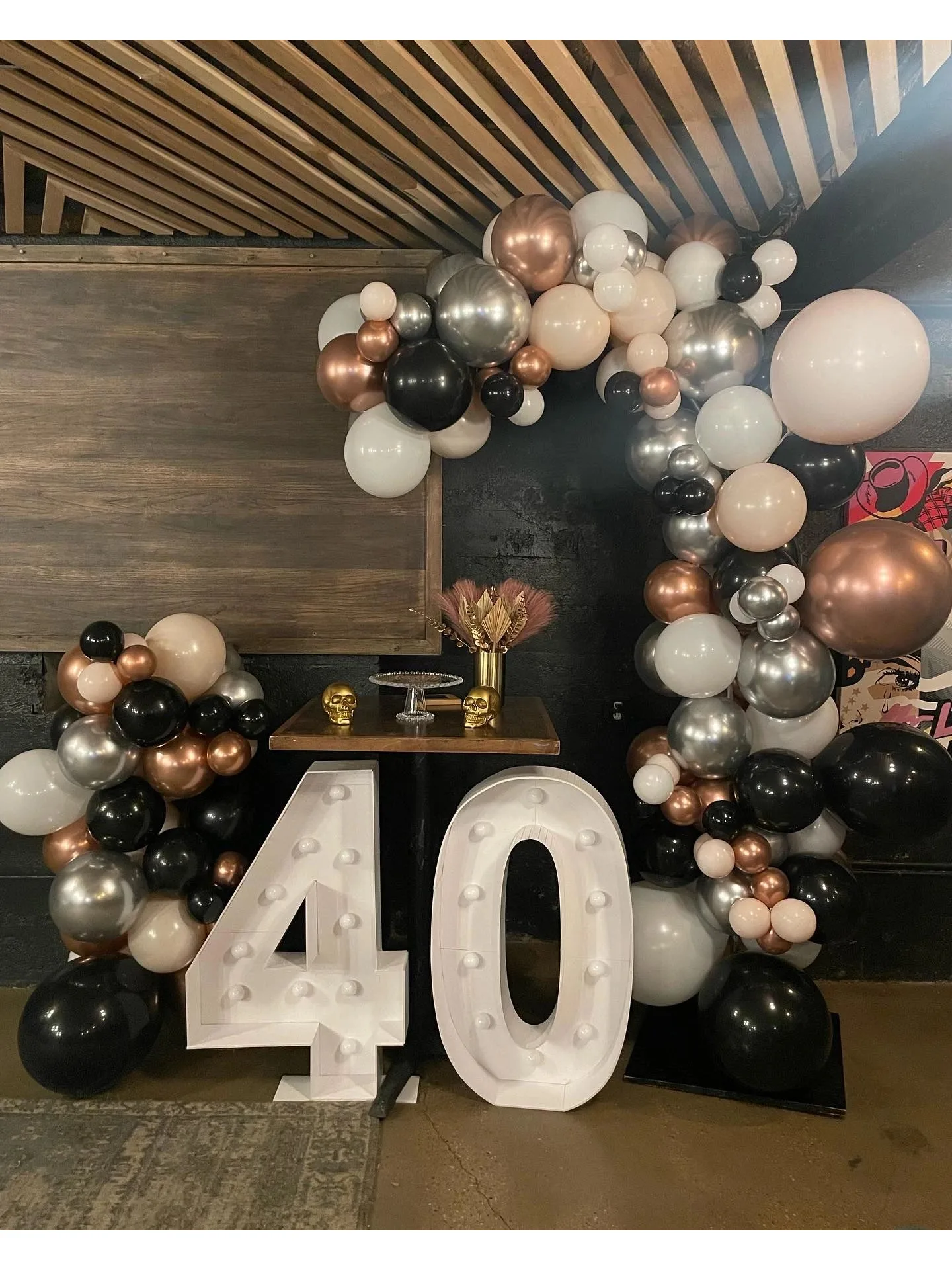Black, blush, and silver balloon backdrop around illuminated number forty