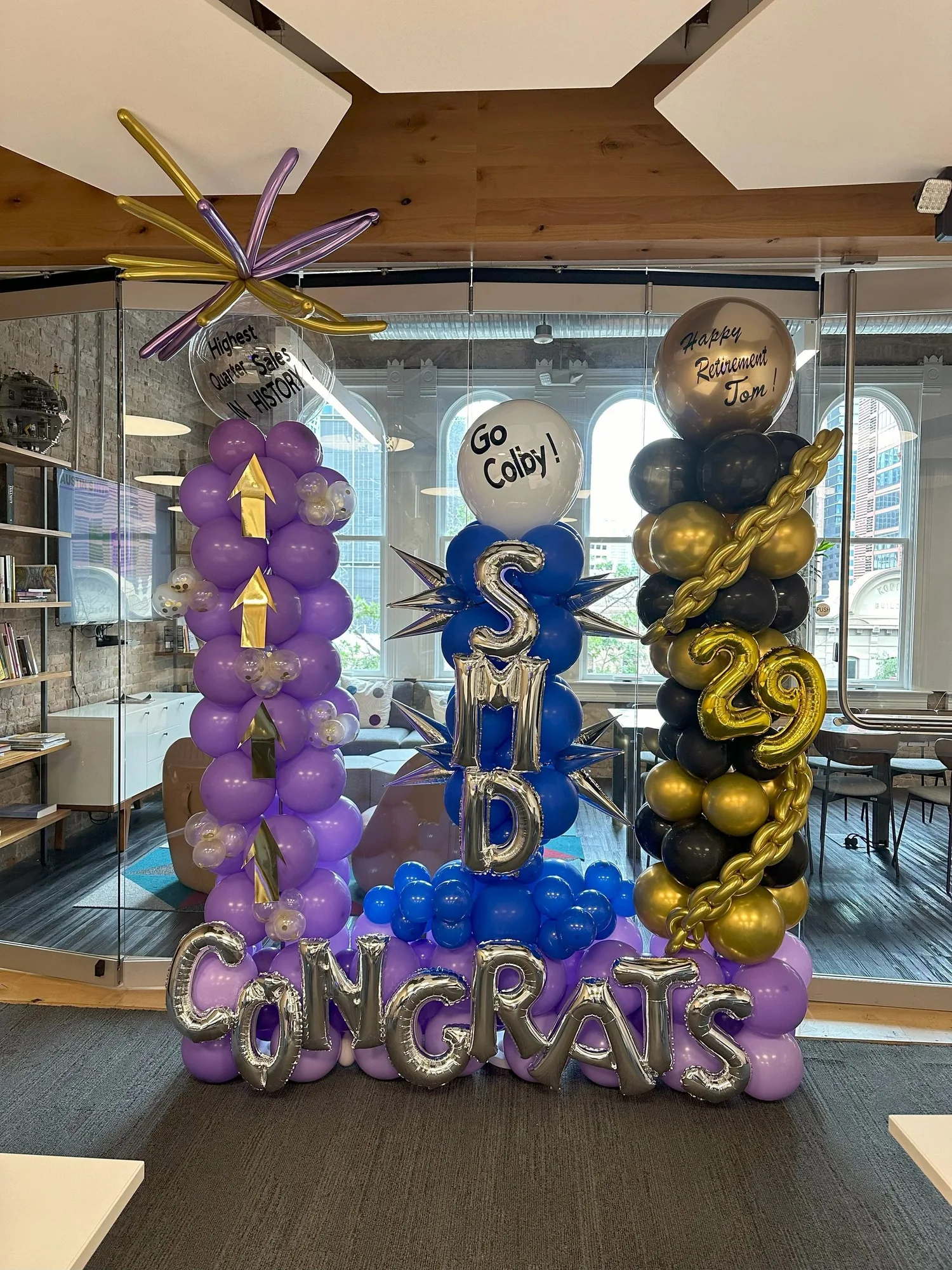 Three purple, blue, black, and gold retirement balloon columns