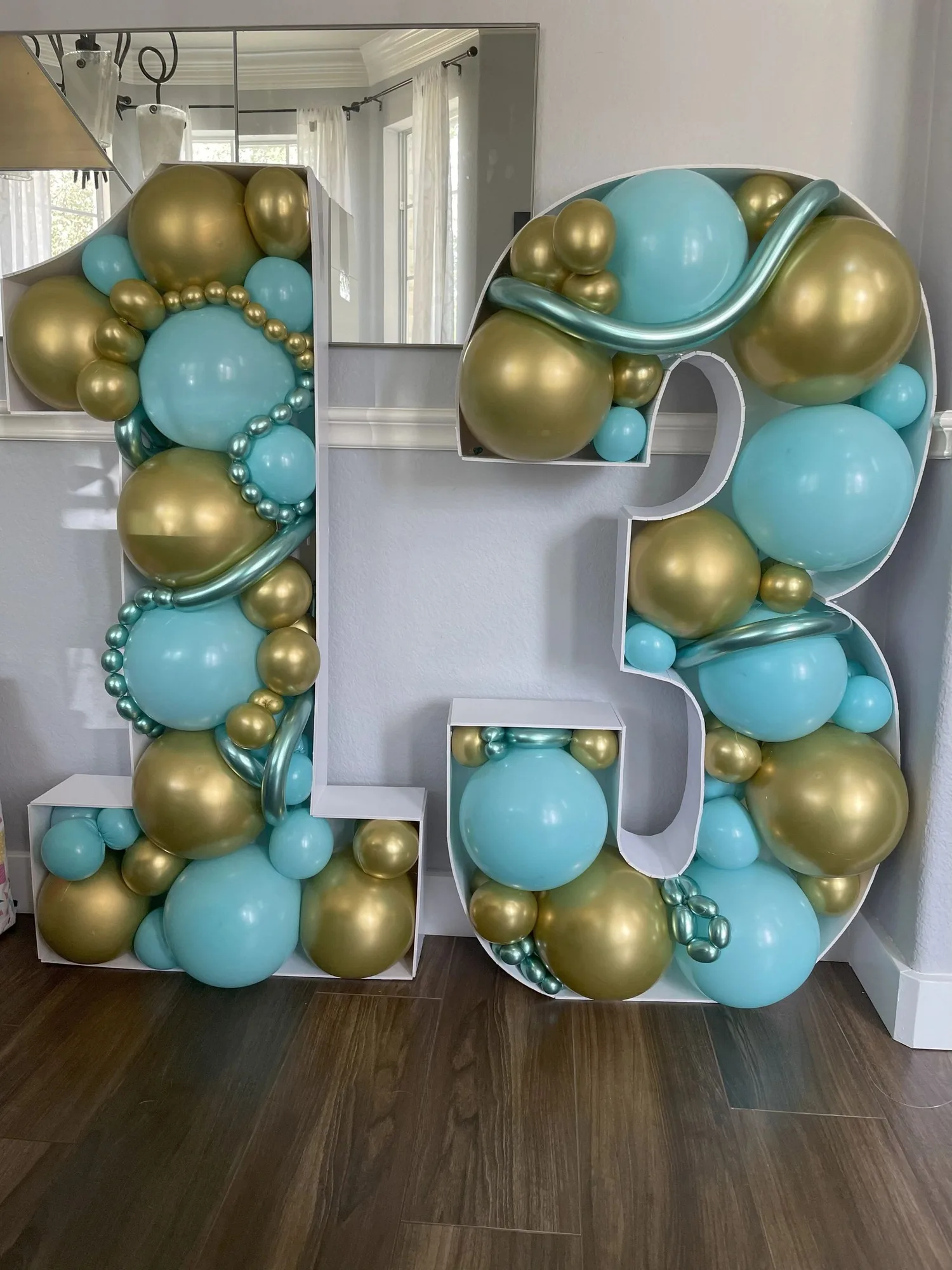Aqua and gold balloons arranged inside number thirteen