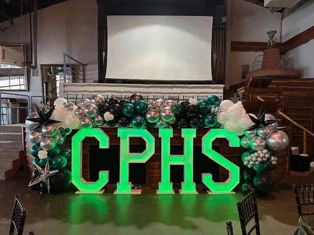 Green, black, silver, and white balloons around illuminated letters