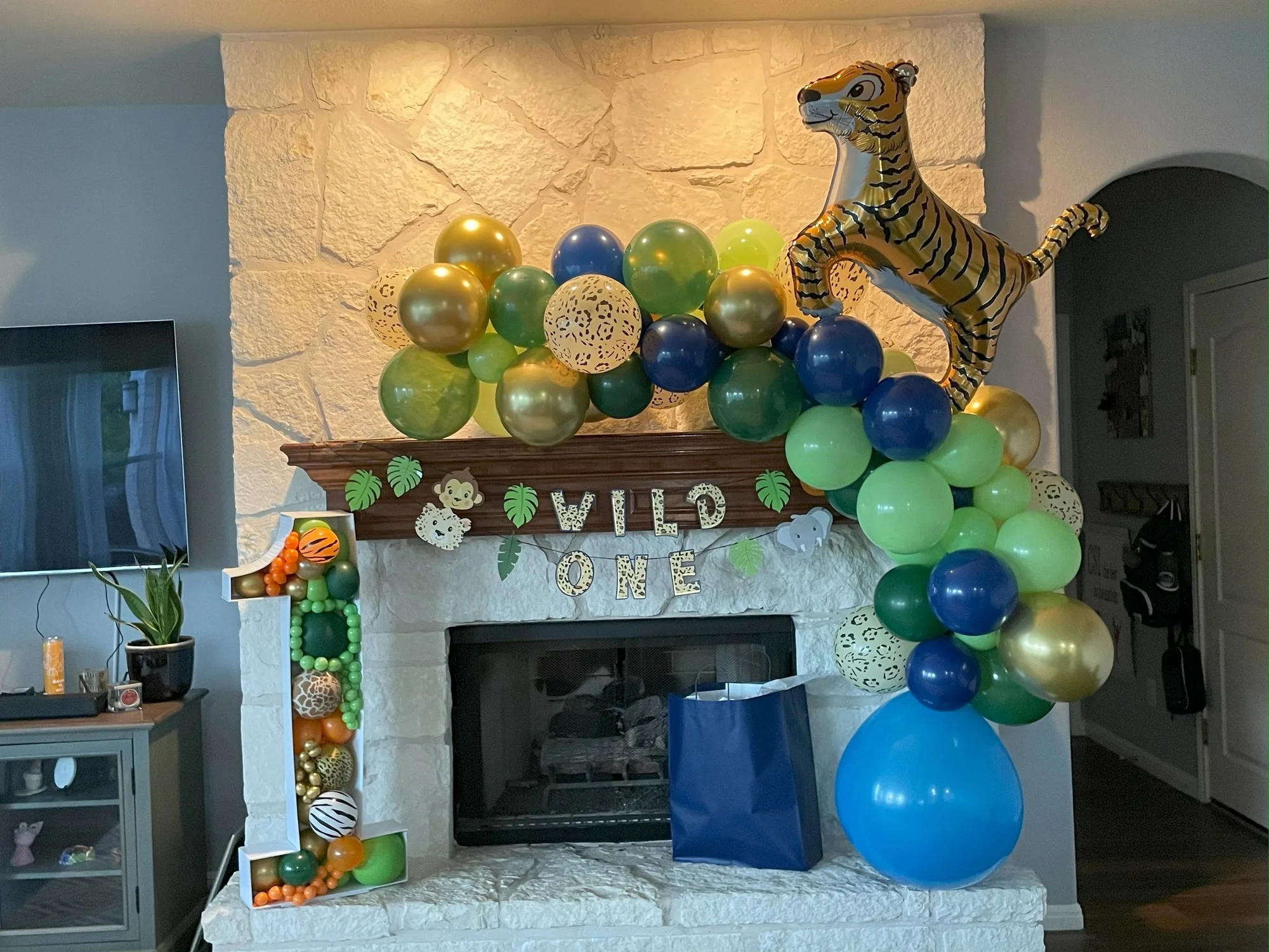 Jungle-themed balloon garland across a fireplace
