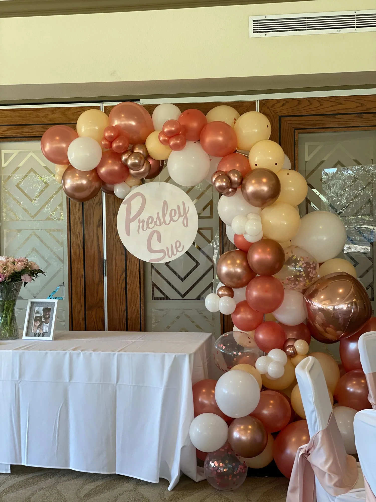 Rose gold, coral, white, and neutral balloon garland beside a table