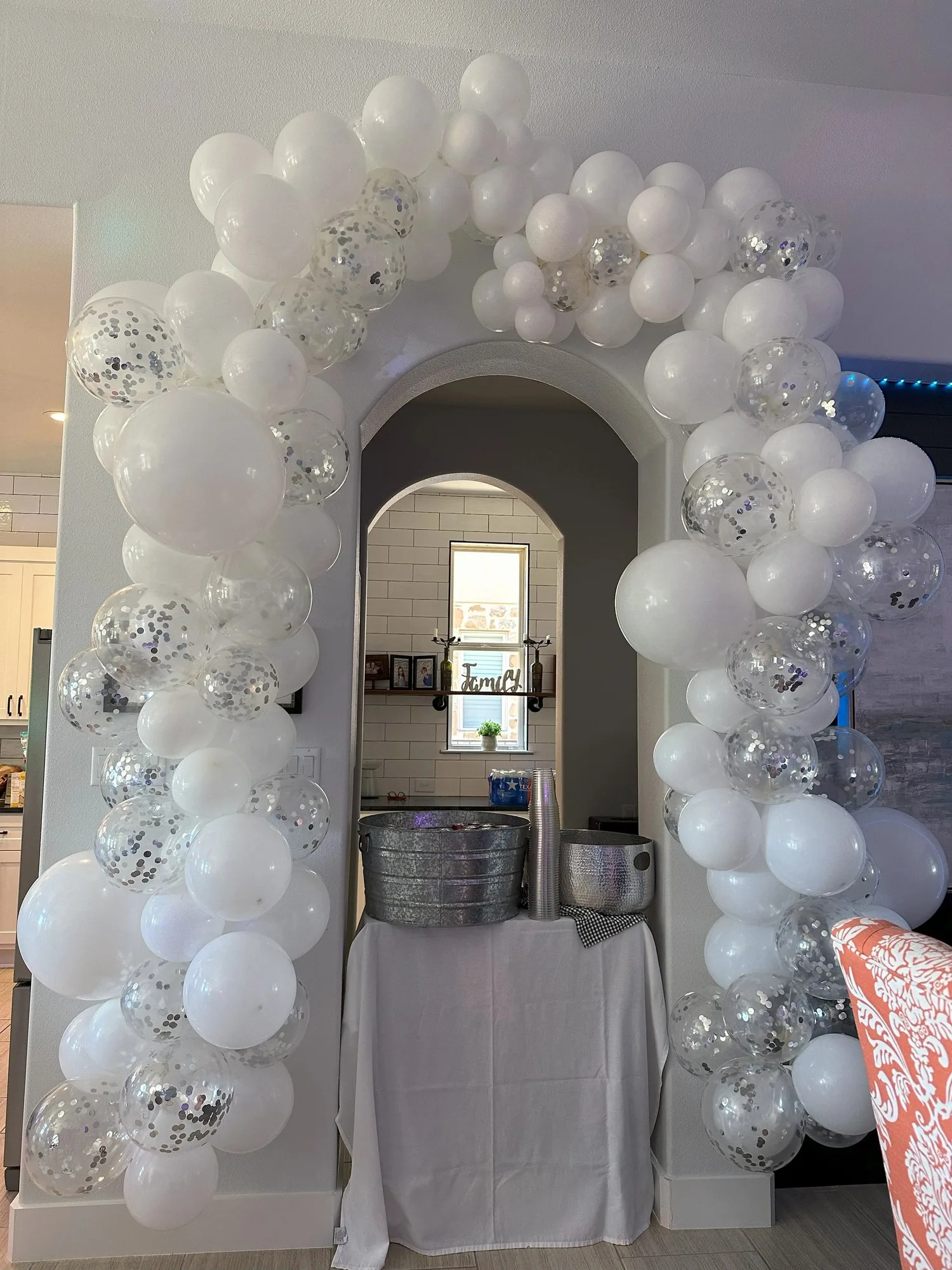 White and silver confetti balloon garland around an interior doorway